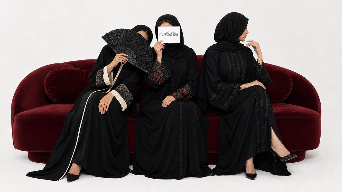Trois femmes portant des abayas Abayina noires élégantes, confectionnées à Médine, assises sur un canapé bordeaux