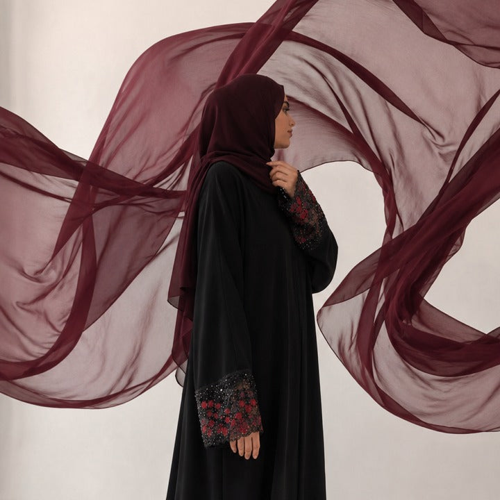 Femme portant une abaya Abayina noire avec voile bordeaux et manches brodées, nouvelle collection